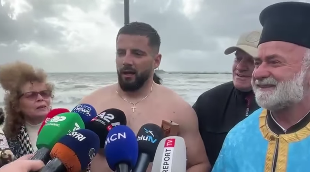 Mario Nesturi kap kryqin mes dallgëve të forta në ceremoninë e Ujit të Bekuar